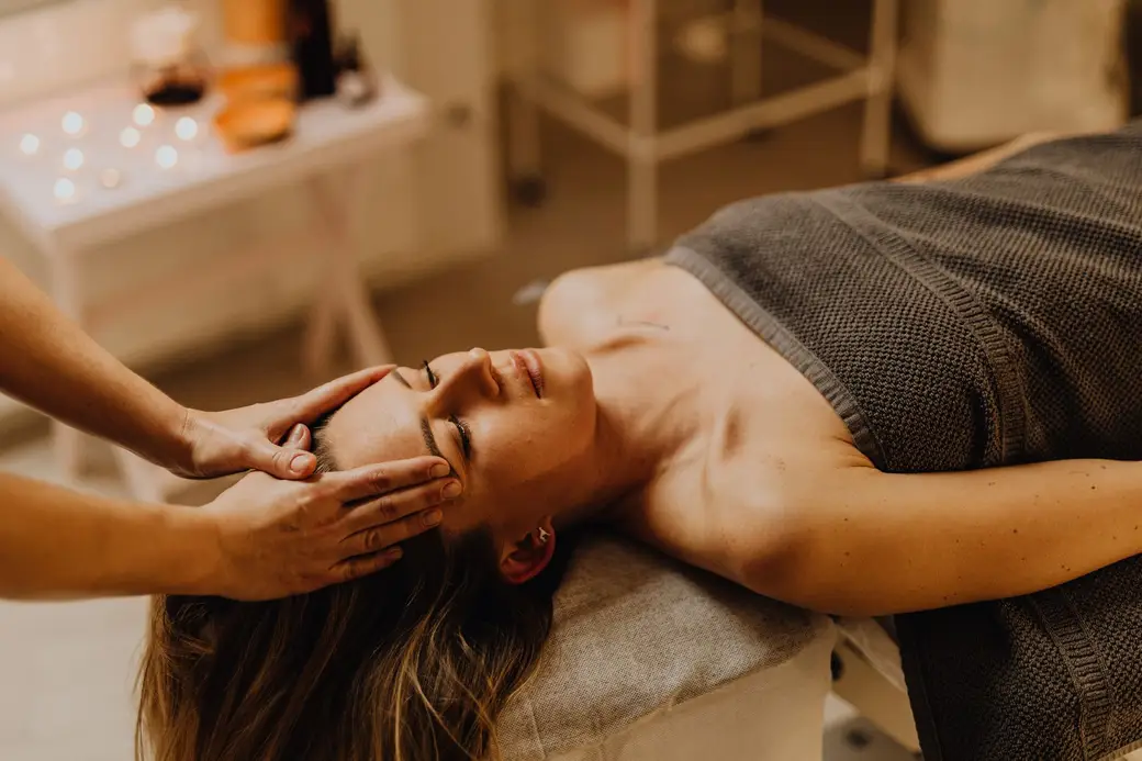 Un soin du visage en cours, les mains de l'esthéticienne posées sur les tempes.