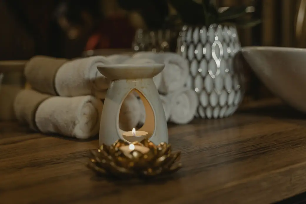 Des serviettes roulées et un brûle-parfum allumé sur une table en bois.