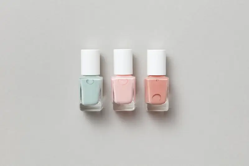 Trois flacons de vernis pastel alignés sur un fond neutre.