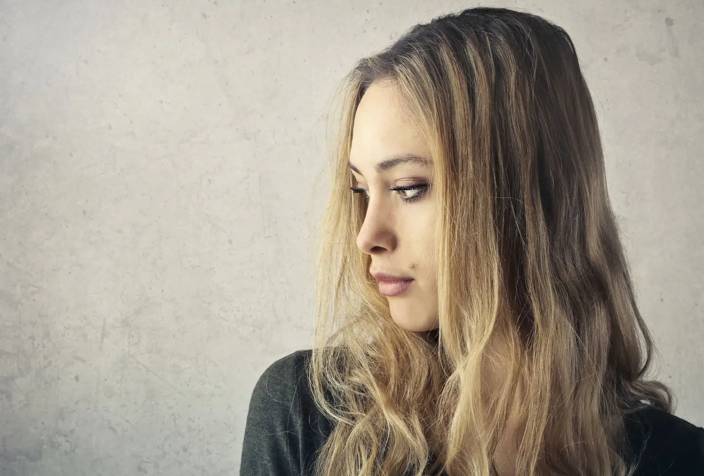 Un balayage blond sur base foncée, vu de profil sur fond neutre.